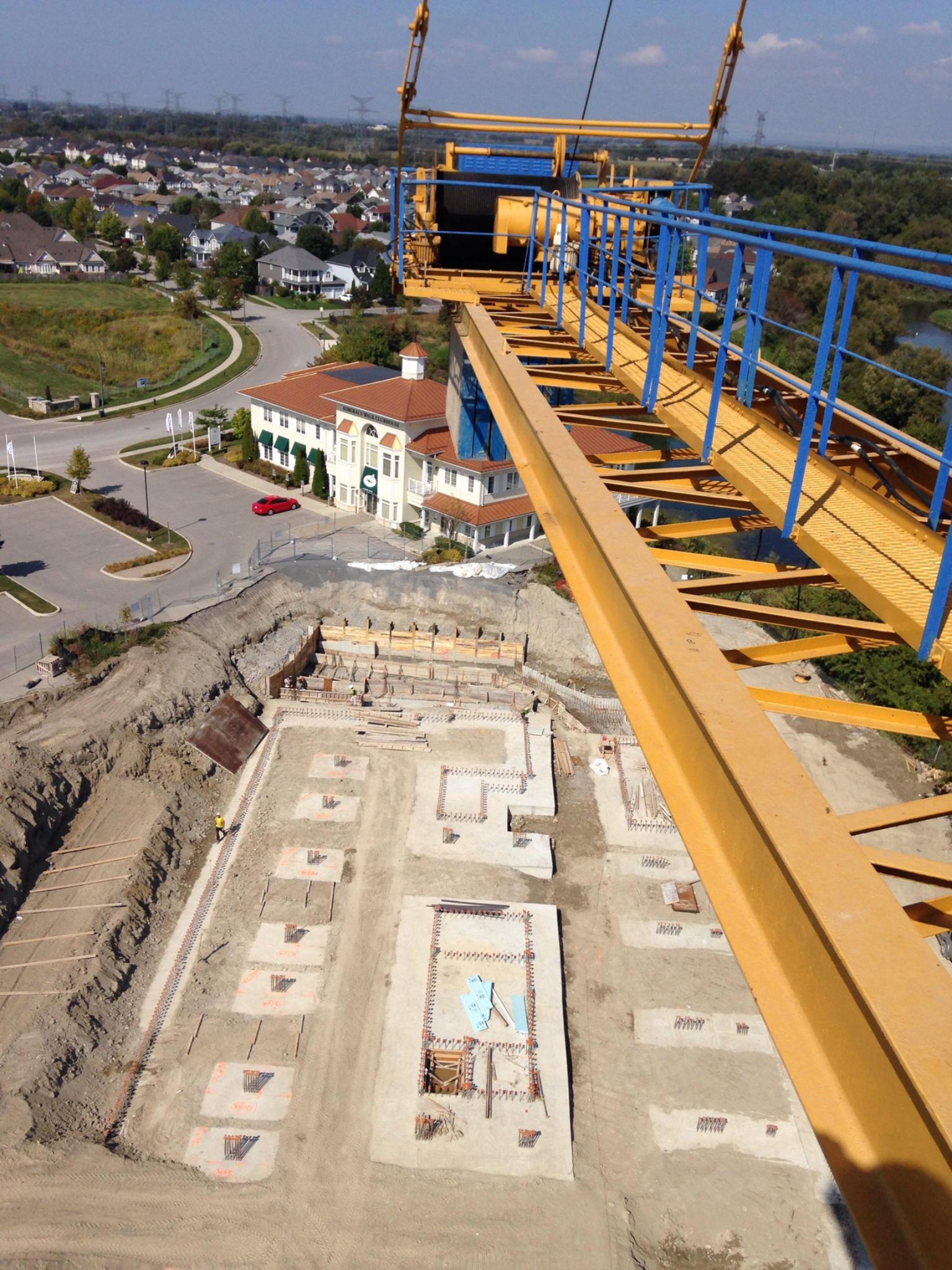 Aerial view of a large concrete foundation excavation with crane access and layout staging