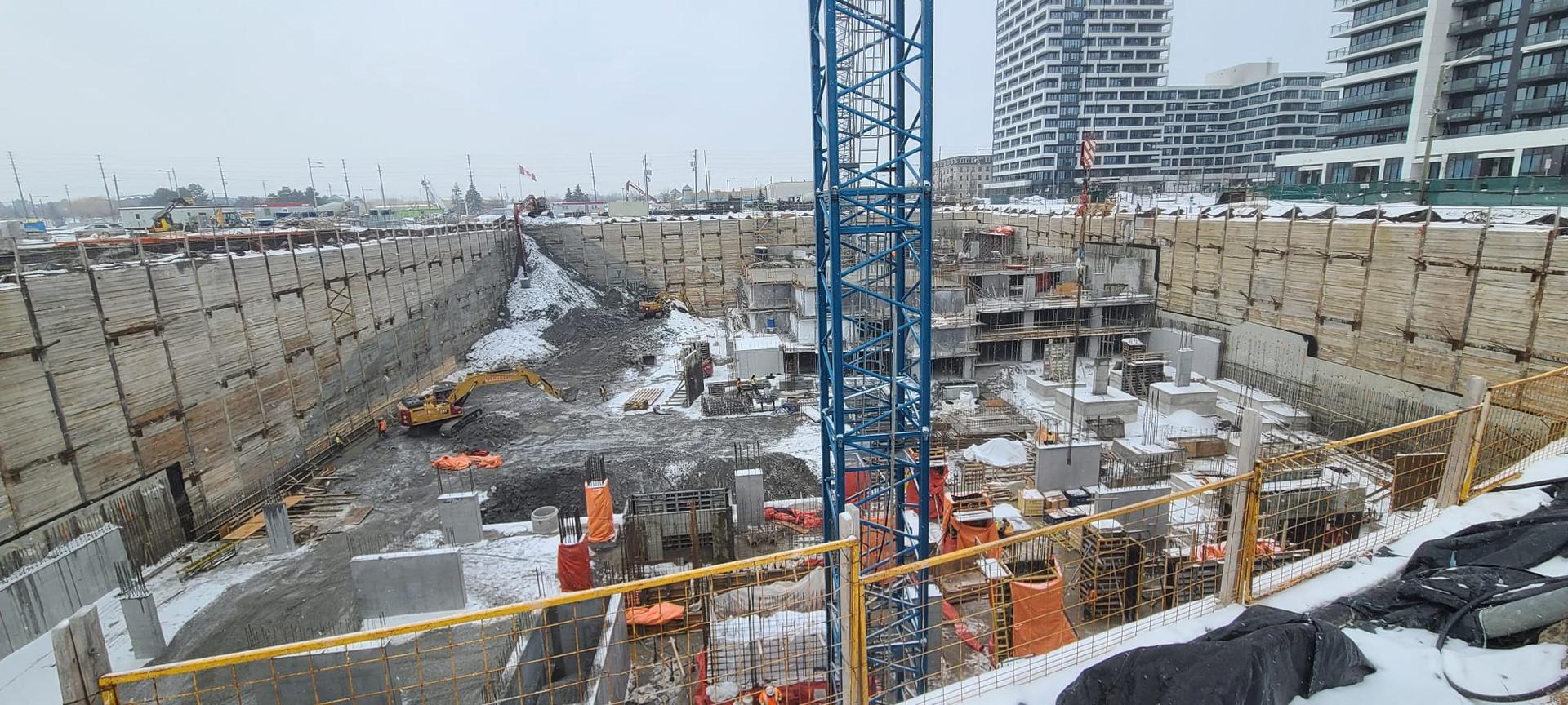 Large foundation excavation with crane access, rebar activity, and concrete forming progress