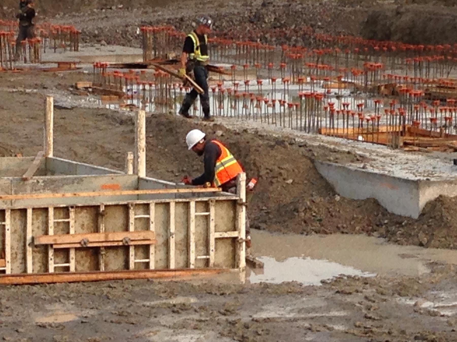 Crew members aligning concrete formwork and reference points during a slab edge pour