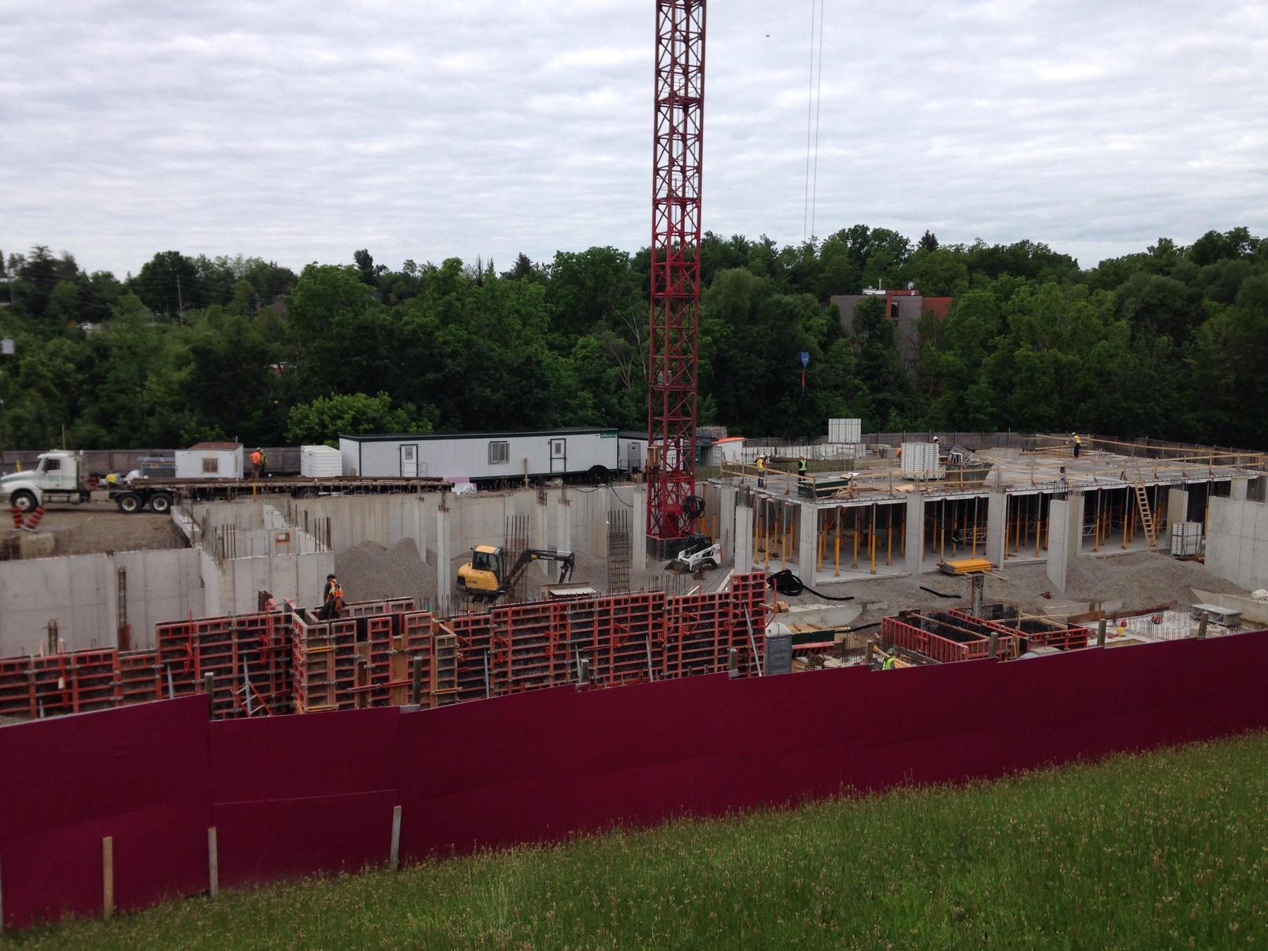 Wide shot of an active concrete forming project with crane operations and perimeter screening