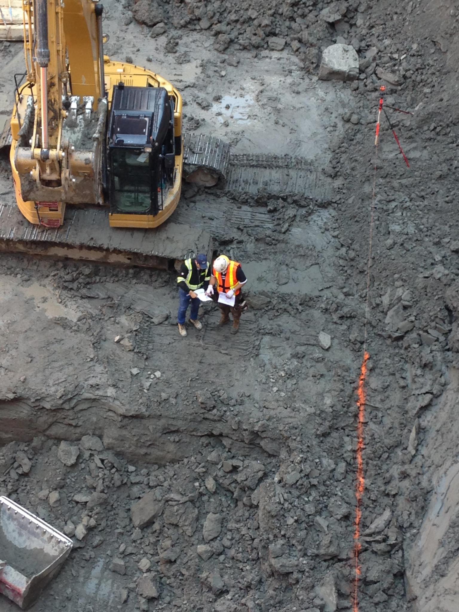 Excavation crew working beside survey control points on a rough graded construction site