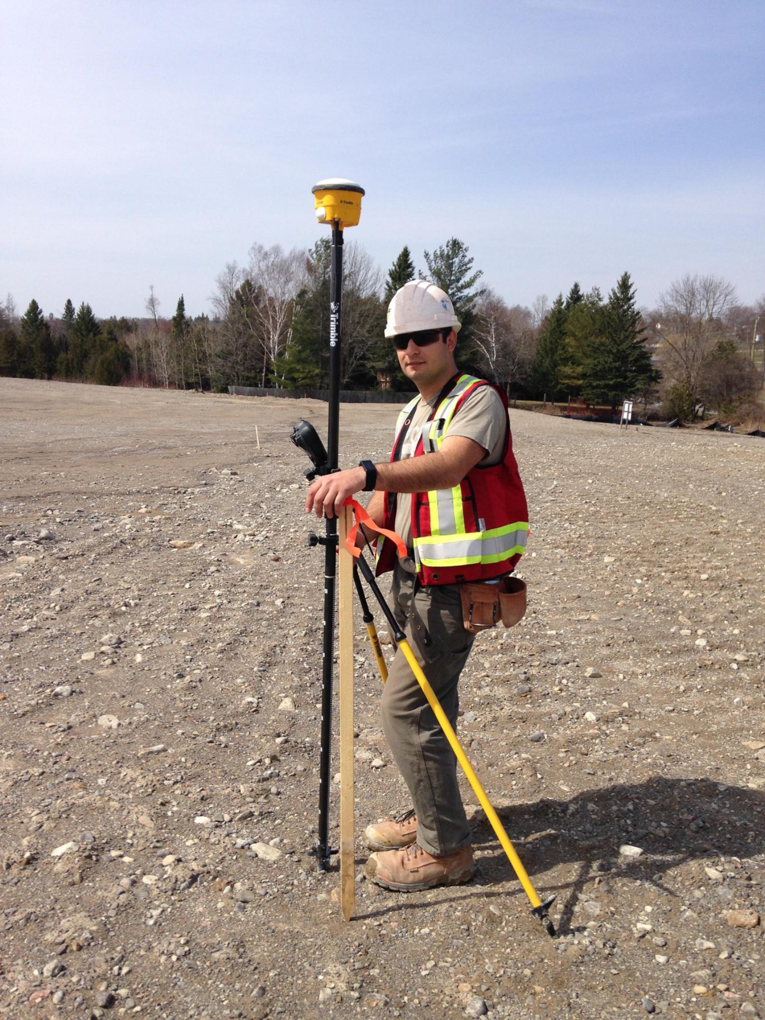 Survey technician operating GNSS equipment for site control and field layout in open terrain
