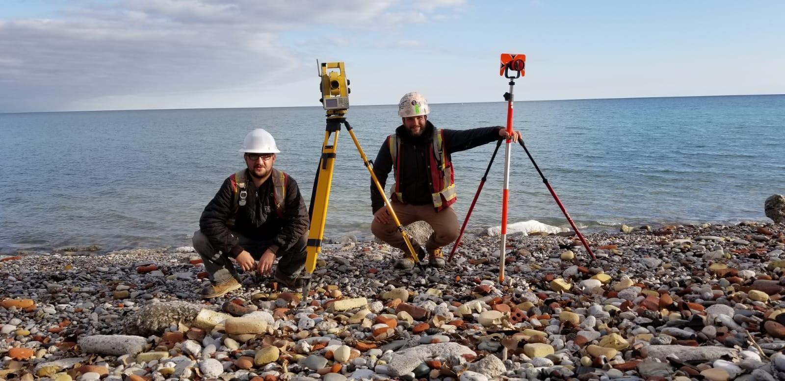 Survey crew performing a shoreline topographic survey with tripods and field instruments